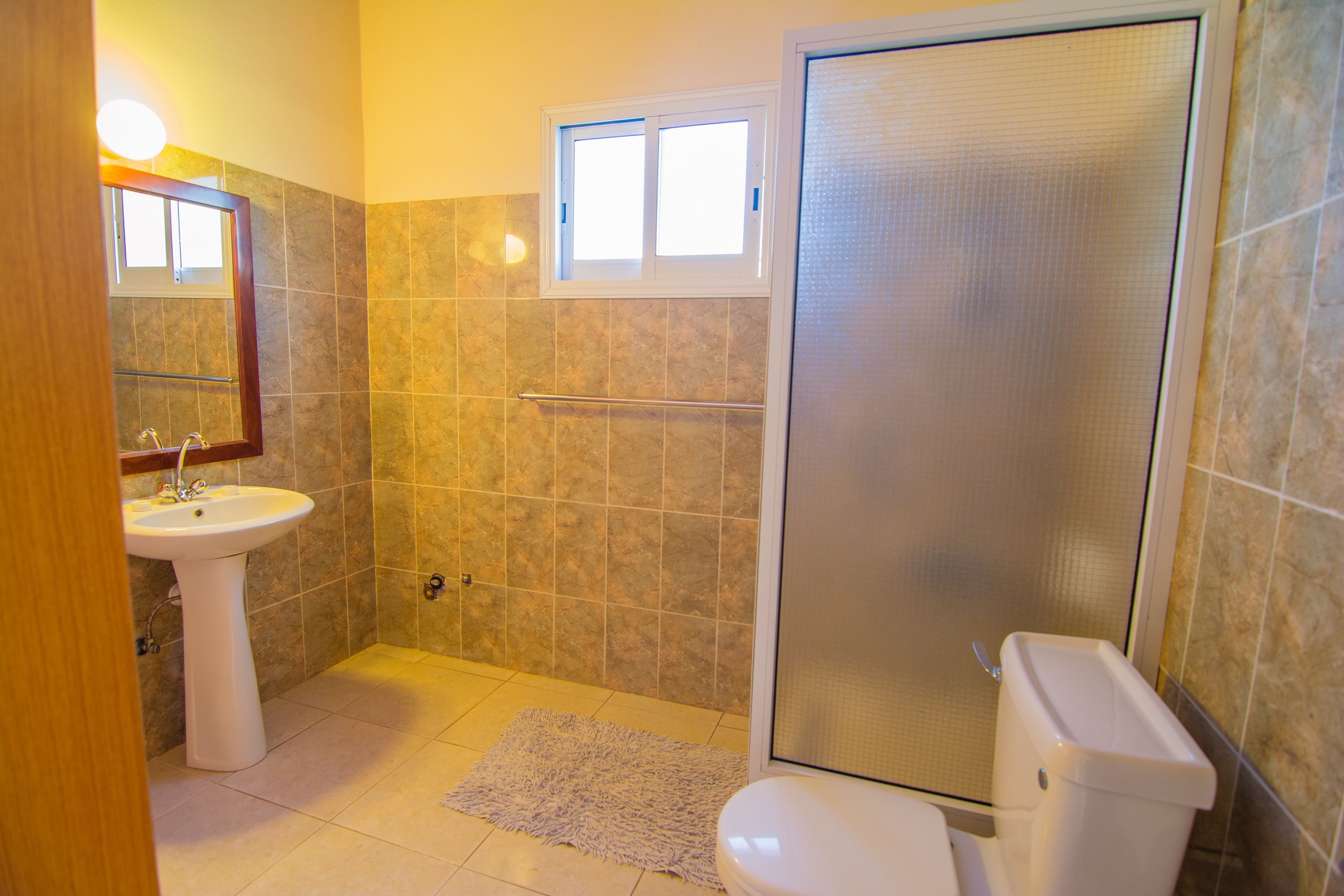 A bathroom with a pedestal sink, a toilet, and a shower enclosure.