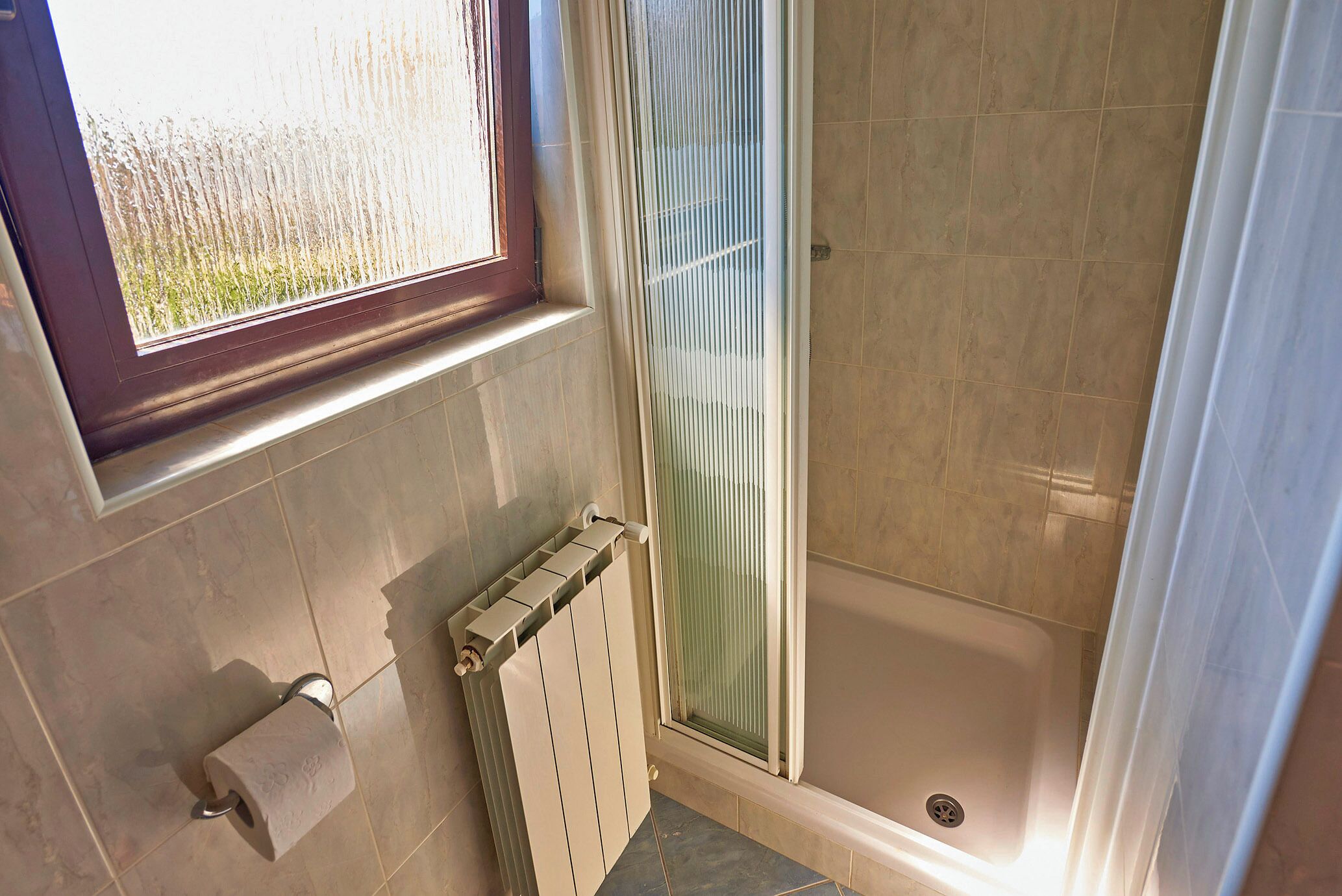 A bathroom with a bathtub, a toilet, a window, and a radiator.