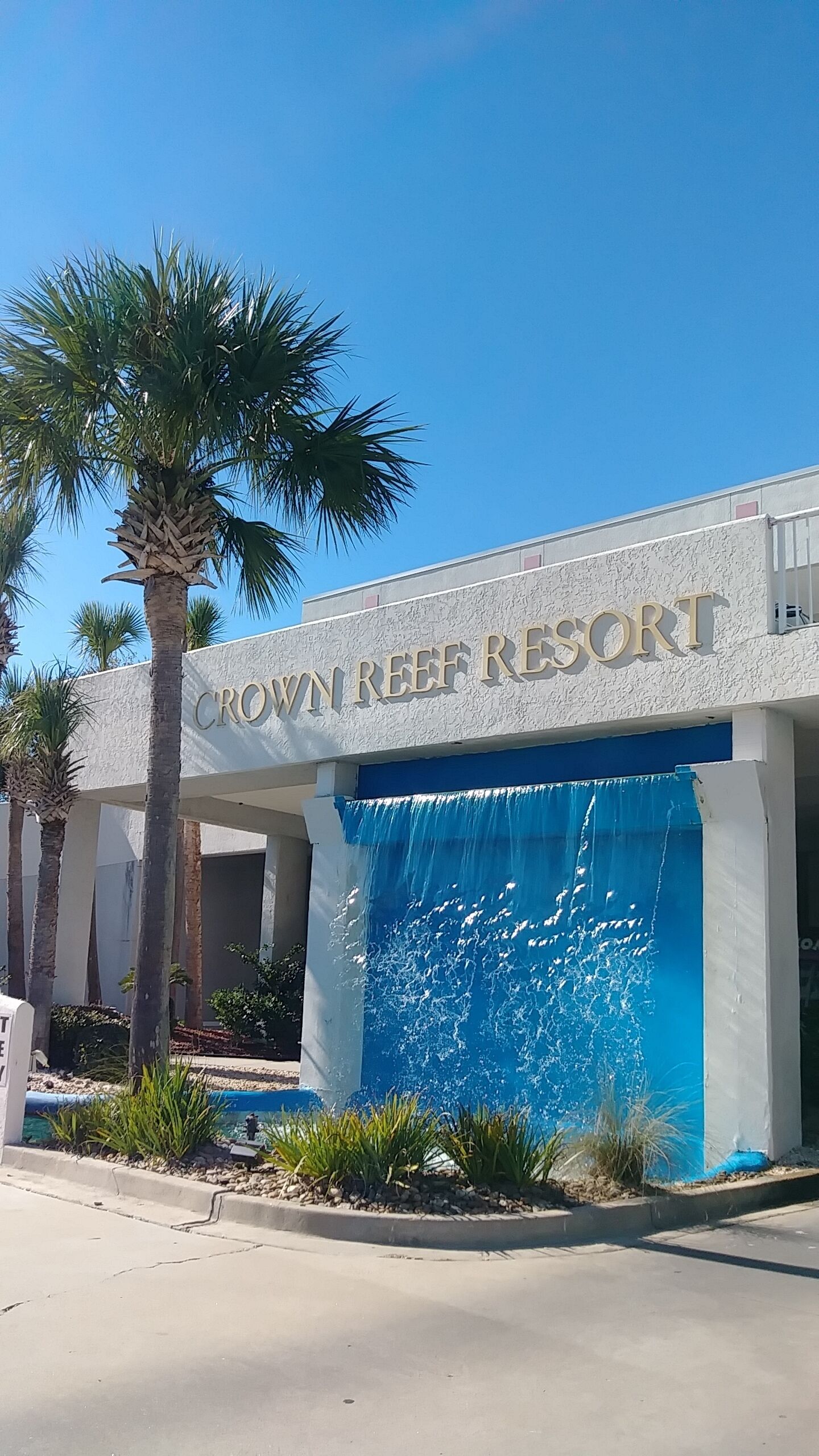 The exterior of Crown Reef Resort with a large water feature in front.