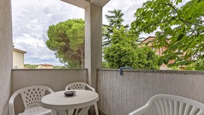 A covered outdoor seating area with a round table and two chairs, a concrete wall, and a view of surrounding buildings and trees. - Liliana in Medulin - Istrien / Liliana in Medulin - 1 Appartement für 2 Personen AP2 (Medulin)