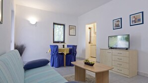 A living room with a sofa, a dining table, chairs, a TV, and a cabinet. - Liliana in Medulin - Istrien / Liliana in Medulin - 1 Appartement für 2 Personen AP2 (Medulin)