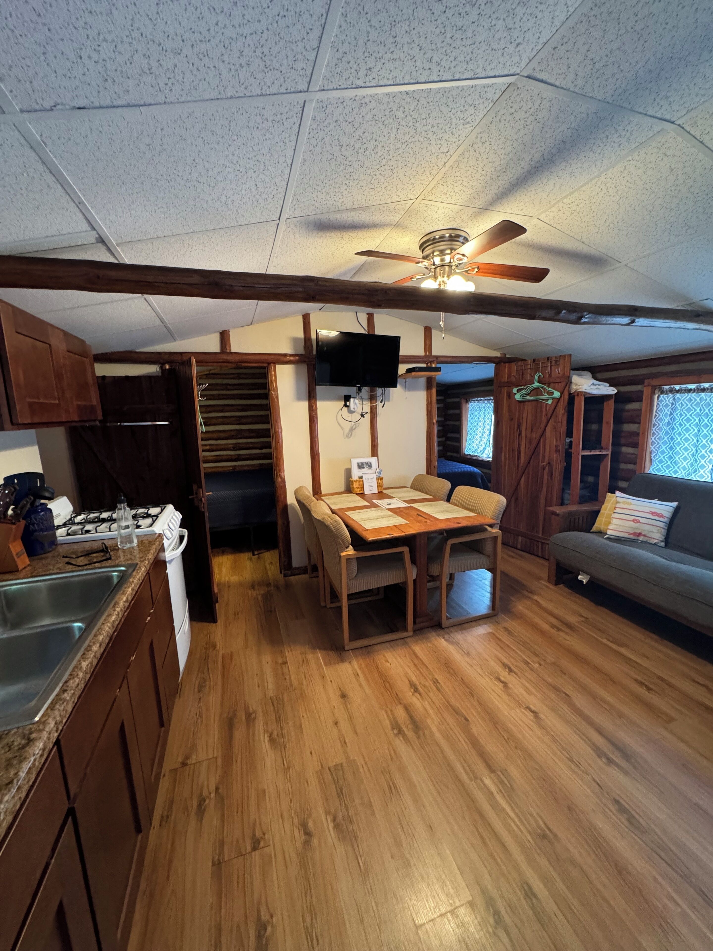 A compact kitchen with a dining table, wooden cabinets, a stove, and a ceiling fan.