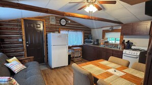 Cocina compacta con refrigerador, microondas, estufa y armarios de madera.