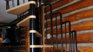 Eine Wendeltreppe mit Holzhäuschen und schwarzen Metallgeländern in einem Blockhaushaus-Interieur.