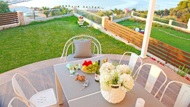 A dining area with a table set for two, overlooking a scenic view of the sea.