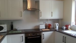 A kitchen with white cabinets, a stainless steel range hood, a toaster, a kettle, and a coffee maker on the counter. - Spacious  holiday cottage in Bowness on Windermere, Lake Distrct, Uk (Windermere)