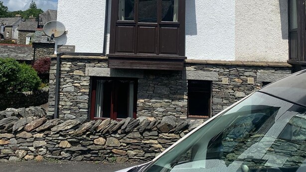 A two-story cottage with a stone foundation, a central bay window, and a satellite dish. - Spacious  holiday cottage in Bowness on Windermere, Lake Distrct, Uk (Windermere)