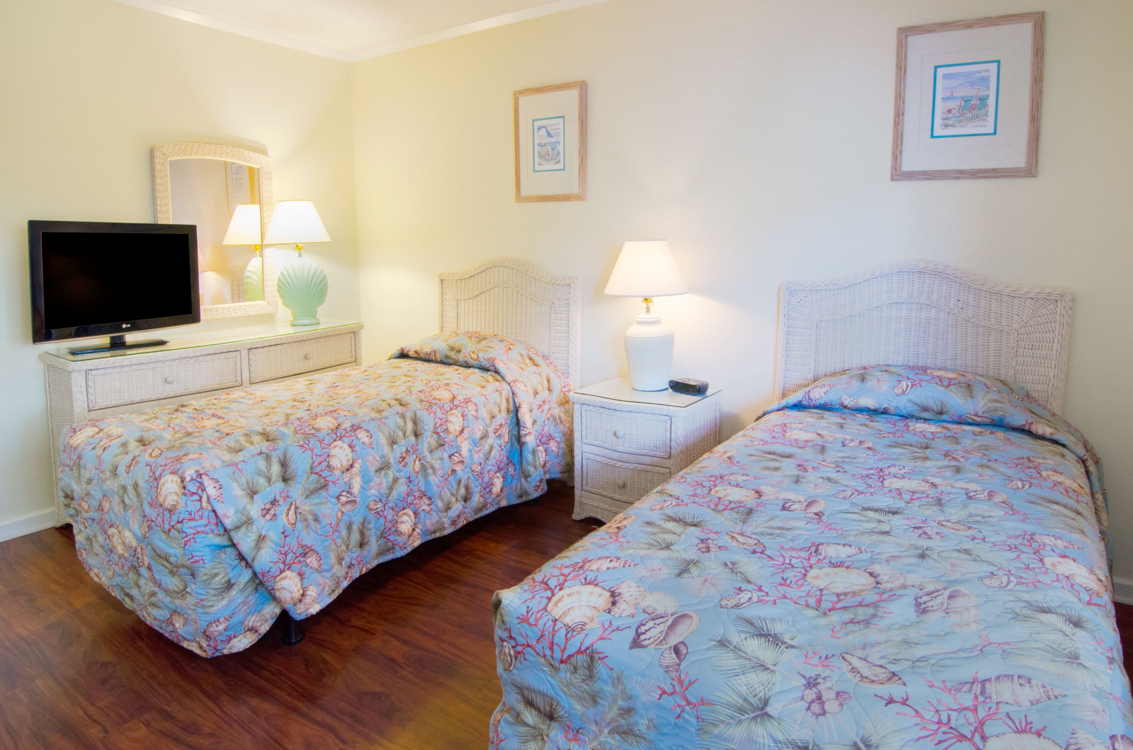 A hotel room with two beds, a television, and two nightstands with lamps.