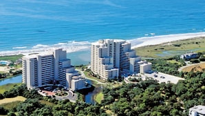 A high-rise hotel with multiple floors, a parking area, and a view of the beach and ocean. - Beautiful Oceanfront Two Bedroom Condo + Official On-Site Rental Privileges (Myrtle Beach)
