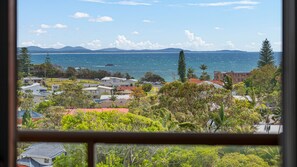 A coastal residential area with houses, a view of the sea, and distant mountains.