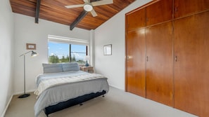 Ein Schlafzimmer mit Bett, Kleiderschrank, Fenster und Deckenventilator.