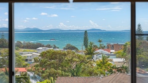 Eine Wohngegend an der Küste mit Häusern, freiem Blick auf das Meer und Bergen im Hintergrund.