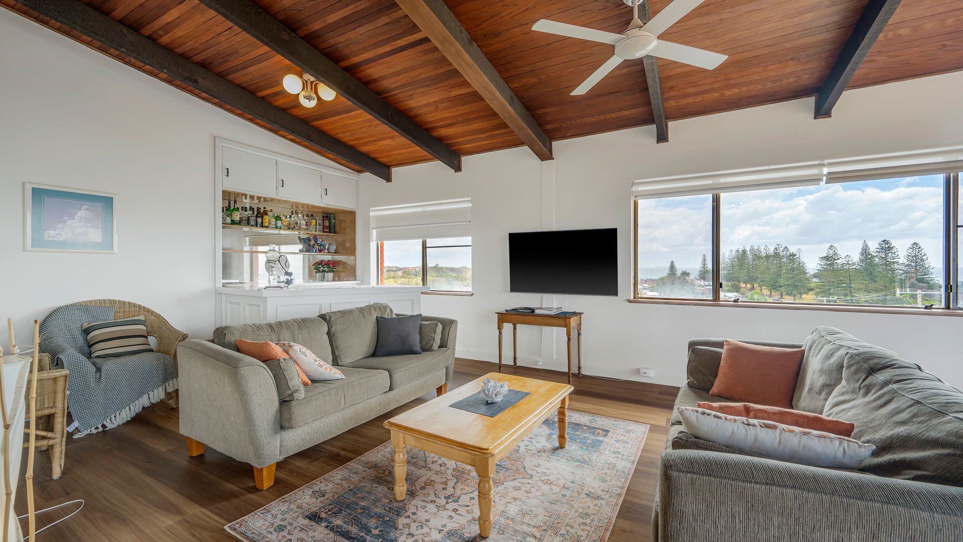 A living room with a sofa, a coffee table, a television, and a view of the outdoors.