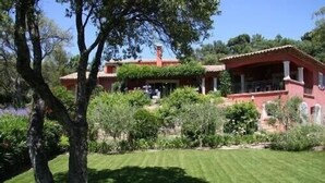 Una villa rossa con un prato curato e verde circostante.