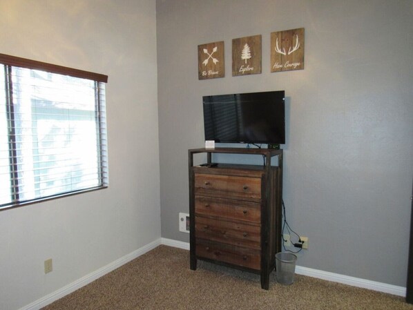 A room with a large window, a wooden dresser, a flat-screen TV on a stand, and three motivational wall art pieces. - Newly remodeled, fully furnished condo located near Pinetop Country Club (Pinetop)