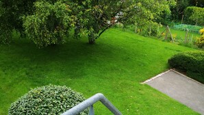 Un jardín bien cuidado con una escalera metálica que conduce a una zona pavimentada.