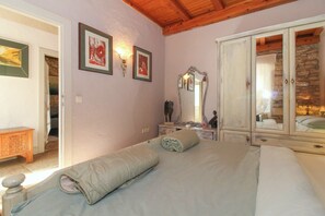 A bedroom with a bed, a dresser, a mirror, and artwork on the wall.