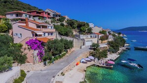 Un pueblo costero con casas a lo largo del mar, agua cristalina y barcos amarrados.
