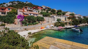Un pueblo costero con casas en una colina, mar azul cristalino y un muelle de madera.