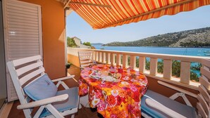 Un balcón con una mesa y dos sillas, con vista a un cuerpo de agua y colinas.
