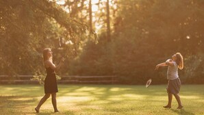 Two people playing badminton in a park with trees and sunlight. - Wooden hut 'Forest bed' near to the river Savinja (Mozirje)