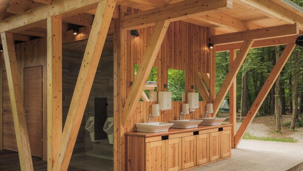 Una cabaña de madera con baño de madera que incluye un lavabo y un inodoro.