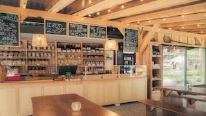 Interior acogedor de un restaurante con vigas de madera, una zona de bar con varias botellas y menús en una pizarra.