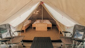 Una tienda de campaña con una cama, dos sillas y una mesa.