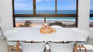 Un comedor con un amplio ventanal con vistas a la playa.