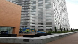 A high-rise building with a playground area in front, including slides and play structures. - CASTLEROCK SUITES AND CONDOS IN MEXICO CITY (México D.F.)