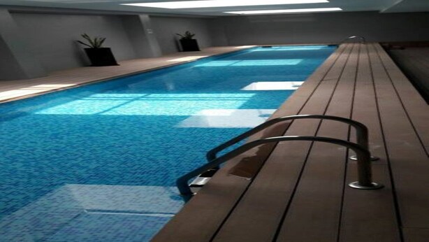 An indoor swimming pool with a wooden deck and a metal handrail. - CASTLEROCK SUITES AND CONDOS IN MEXICO CITY (México D.F.)