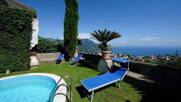 A pool area with blue lounge chairs and a view of the sea and mountains. - Apartment with Private Pool (SCALA)