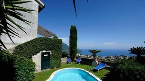 A swimming pool with two lounge chairs, a door, and a view of the sea. - Apartment with Private Pool (SCALA)