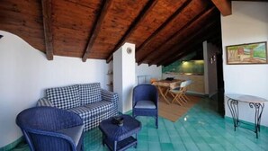 A cozy room with a checkered sofa, a blue armchair, and a small table. A wooden ceiling and a tiled floor are visible. - Apartment with Private Pool (SCALA)
