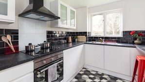 Eine moderne Küche mit weißen Schränken, schwarzen Arbeitsflächen und einem schwarz-weißen Bodenbelag.