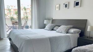 A modern bedroom with a large bed, a nightstand, a lamp, and a view of the outside balcony. - NEW BEAUTIFUL APARTMENT WITH LARGE TERRACE- A CASA DI CAROLINA (Cassino)