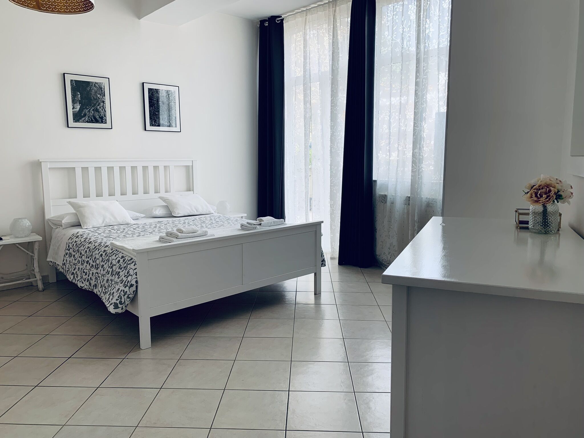 Een moderne slaapkamer met een wit bed, een nachtkastje en een klein bureau.