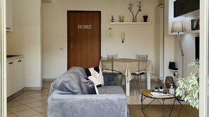 A modern living room with a grey sofa, a dining table, and a kitchen area in the background. - NEW BEAUTIFUL APARTMENT WITH LARGE TERRACE- A CASA DI CAROLINA (Cassino)