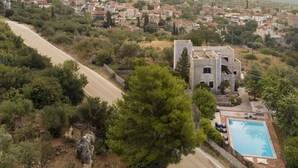 A coastal village with a prominent building featuring a swimming pool and outdoor seating. - Luxurious Mani Peninsula Traditional Tower (East Mani)
