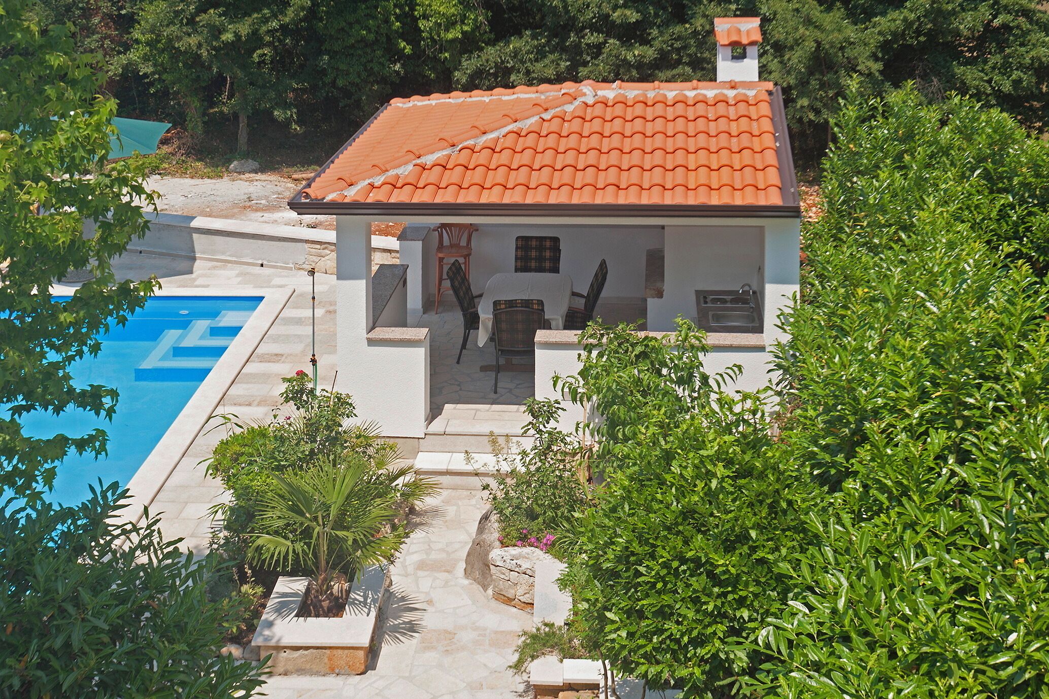 A villa with a swimming pool, outdoor seating, and lush greenery.
