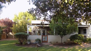 Ein Haus mit Vordergarten, einem kleinen Baum und einem gepflegten Rasen.