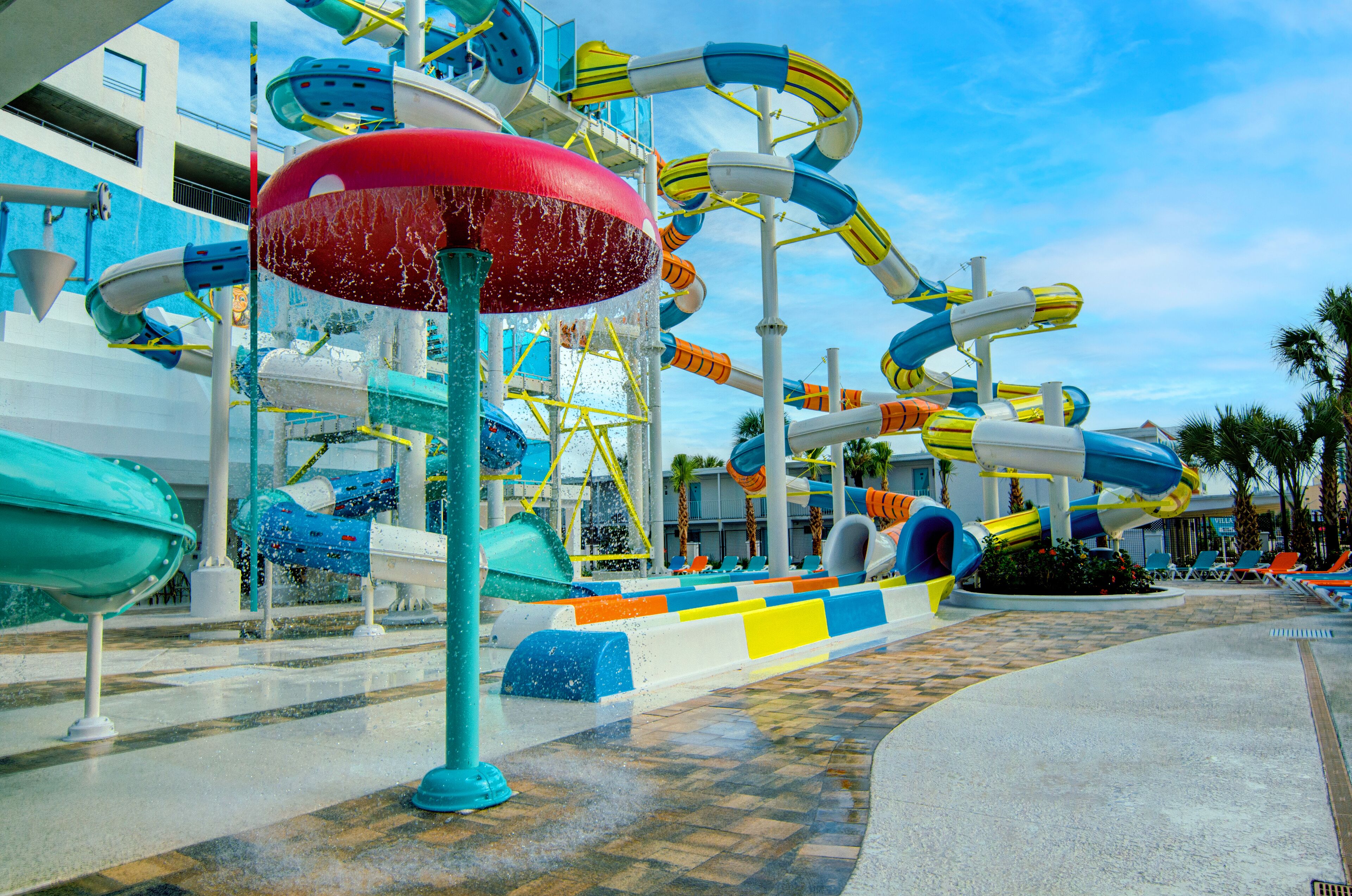 A water park with multiple slides and a large red umbrella structure.