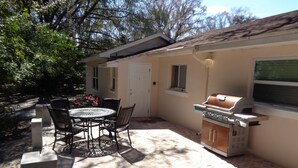 Eine Terrasse mit Grill, Tisch und Stühlen sowie einer Tür.