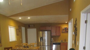Eine geräumige Küche mit Kühlschrank, Herd und Essbereich mit Stühlen und Tisch.