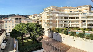 Un edificio residencial de varios pisos con balcones, piscina y un jardín bien cuidado.