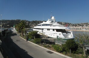 A large white yacht docked at a marina with a clear view of the surrounding area, including a road and buildings in the background.