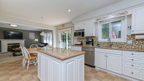 A modern kitchen with white cabinetry, a central island, and a dining area with chairs.
