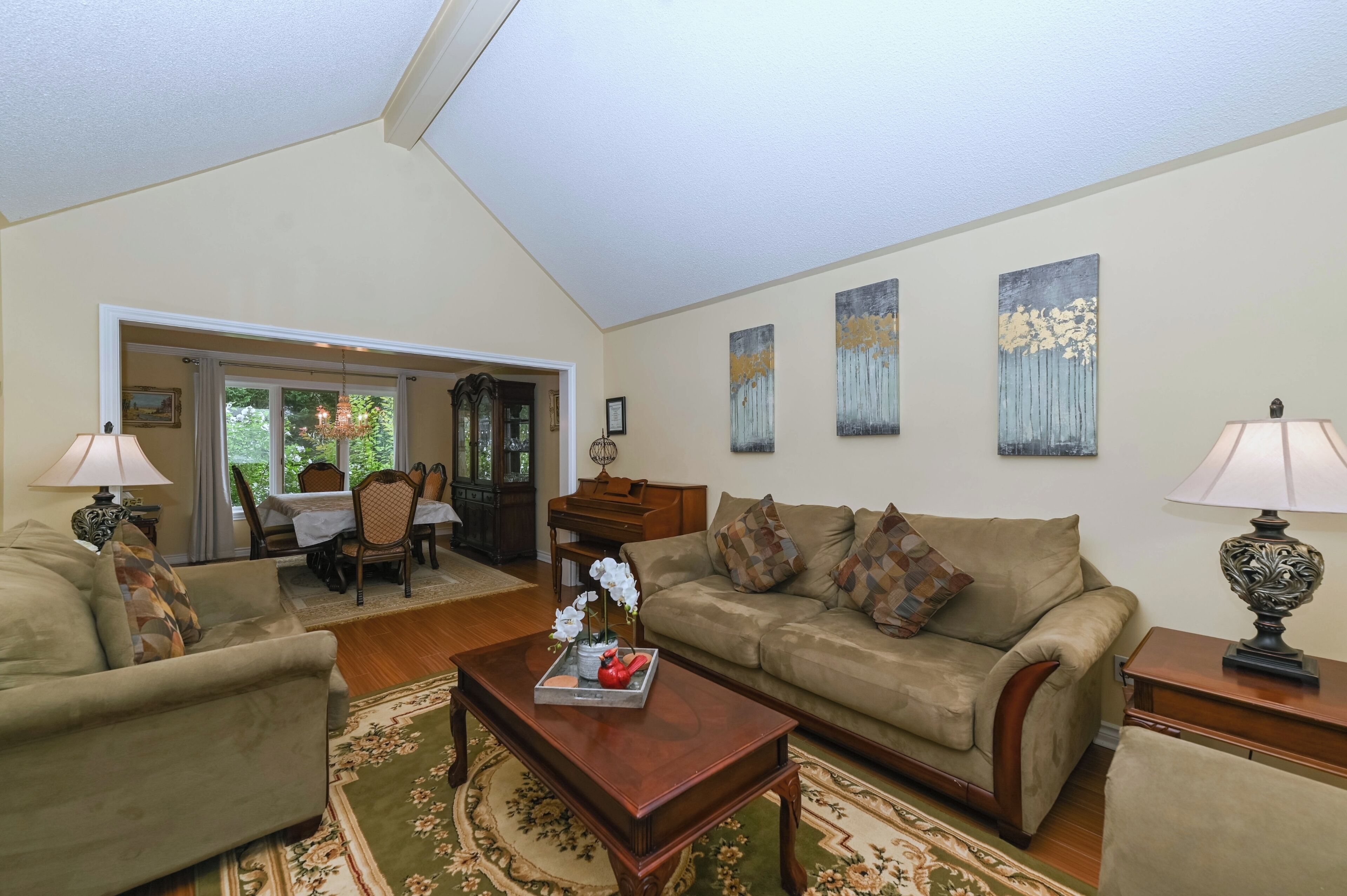 A spacious living room with a high ceiling, a dining area with a table and chairs, and a sofa set.