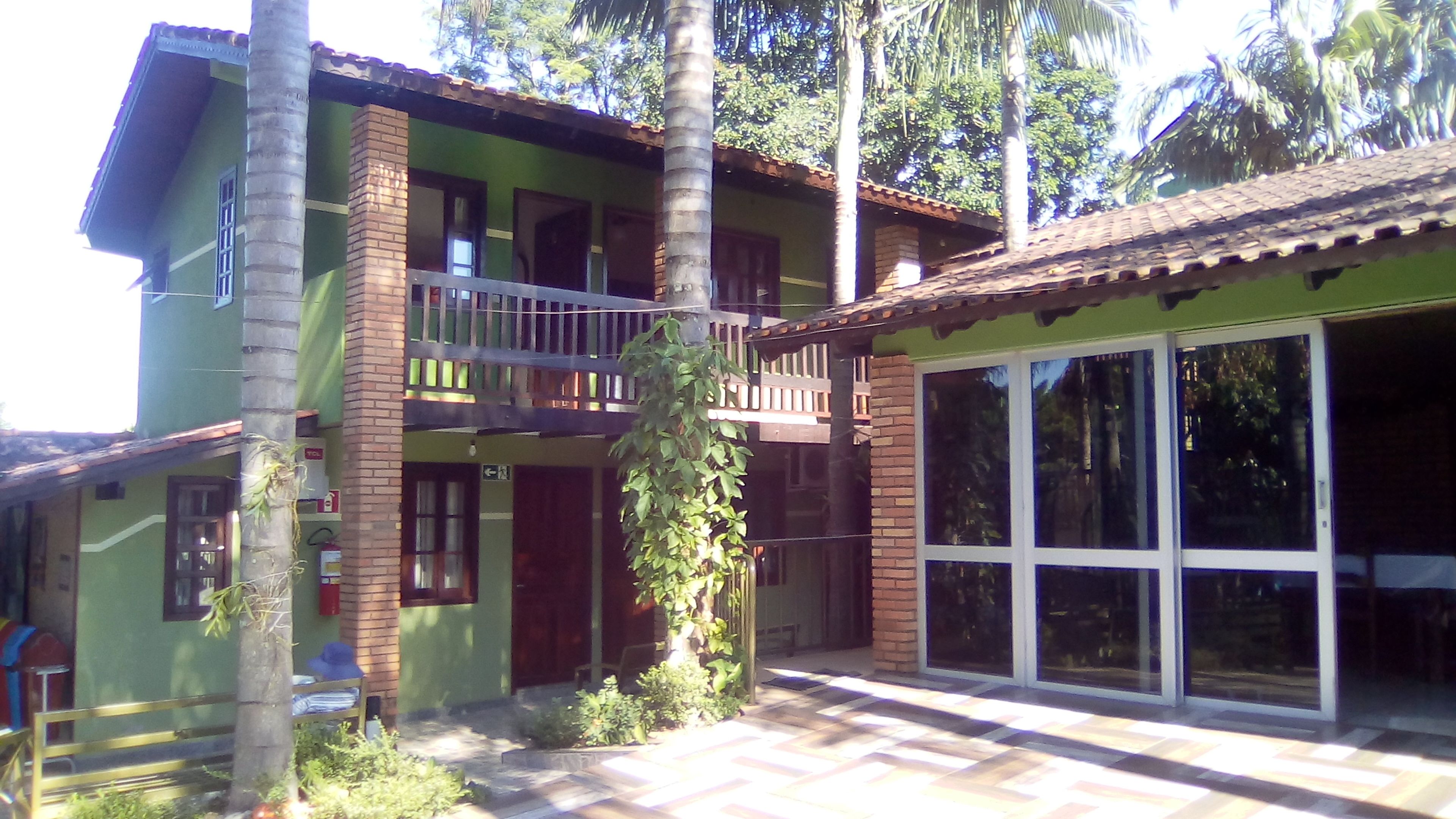Uma casa de dois andares com varanda, janelas amplas e telhado com telhas.