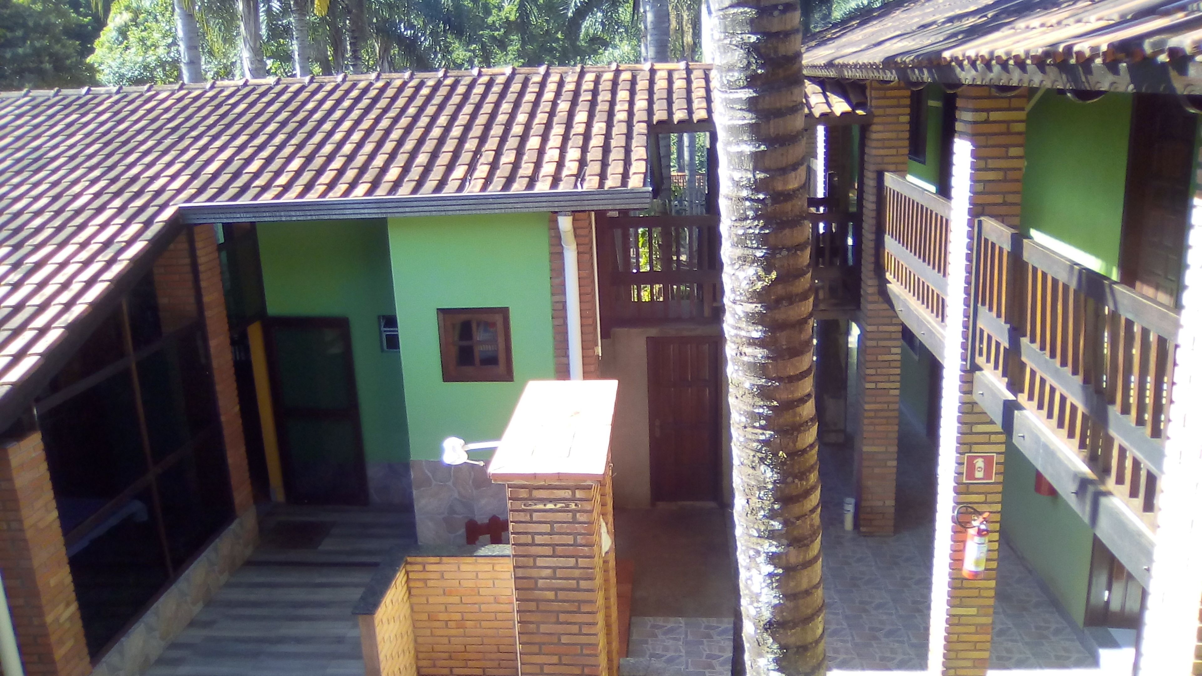 A two-story building with a tiled roof, green walls, and a staircase leading to the upper level.